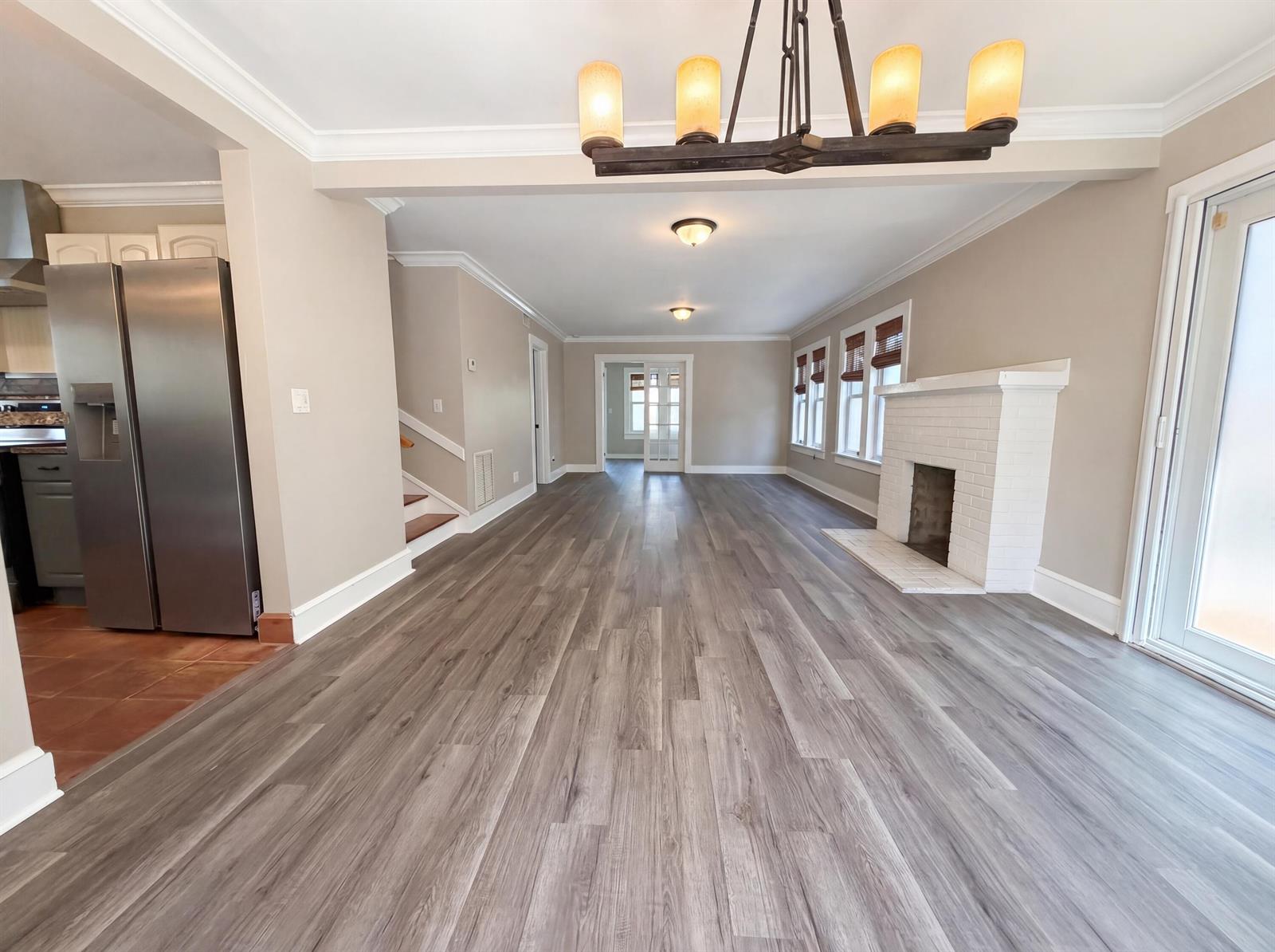A living room with gray wood-look flooring, a white brick fireplace, and a chandelier — 207 S Ocean Breeze, FL 33460, FL