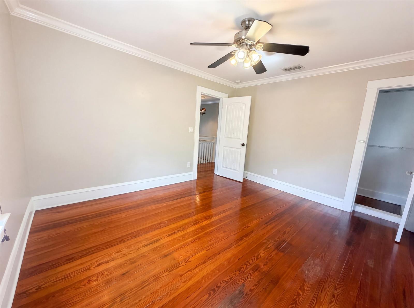 An empty bedroom features hardwood floors, a ceiling fan, and two white interior doors — 207 S Ocean Breeze, FL 33460, FL