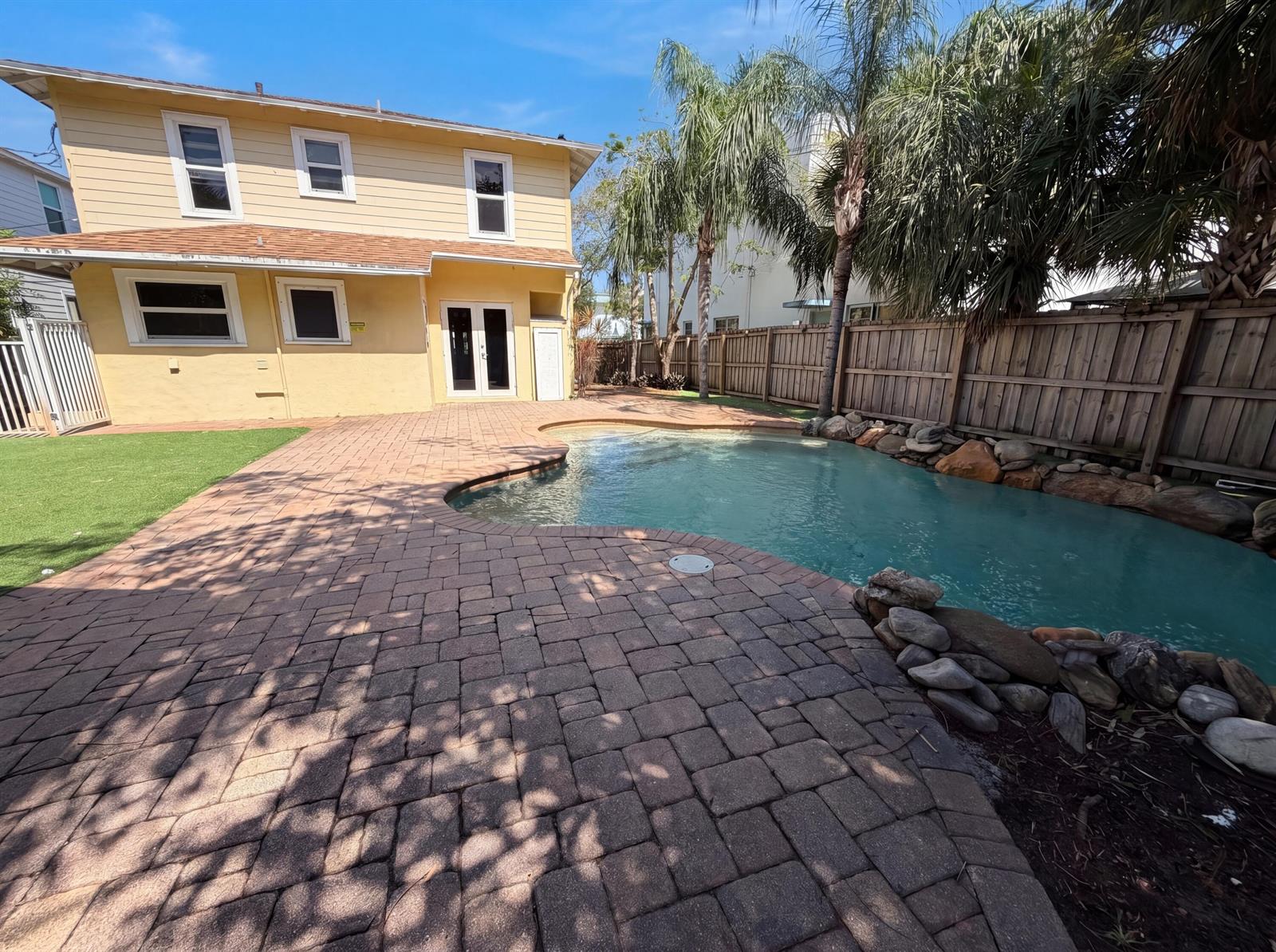 A yellow two-story house features a backyard with a paver patio and a swimming pool — 207 S Ocean Breeze, FL 33460, FL
