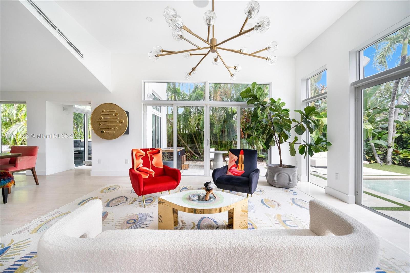 A bright living room features a modern chandelier, two accent chairs, and floor-to-ceiling windows — 520 E Dilido Dr, Miami Beach FL 33139, MIAMI BEACH, FL
