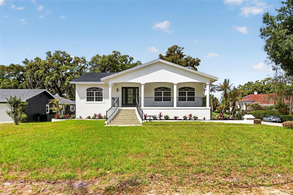 A white, single-story house with a front porch, stairs, and a large grassy lawn — 1002 OAKDALE STREET, WINDERMERE, FL