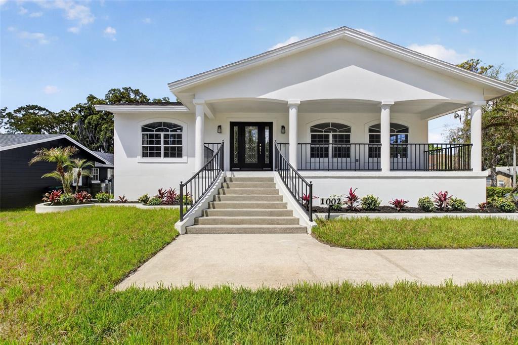 A white house with a covered front porch, black railings, and concrete stairs — 1002 OAKDALE STREET, WINDERMERE, FL