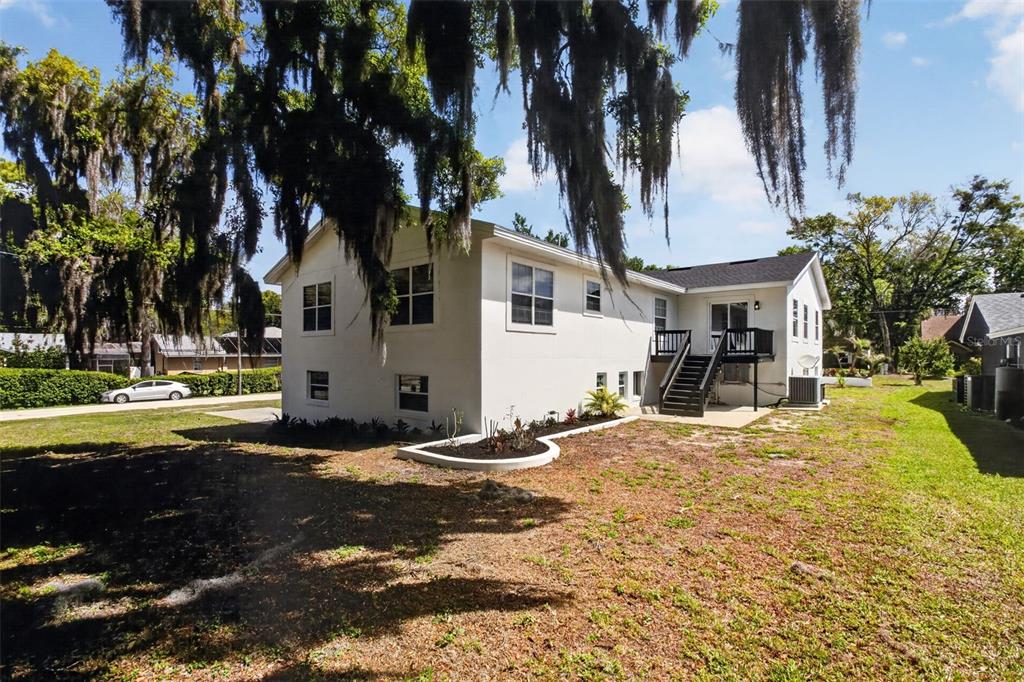 The exterior of a white house with a black deck and Spanish moss-covered trees — 1002 OAKDALE STREET, WINDERMERE, FL
