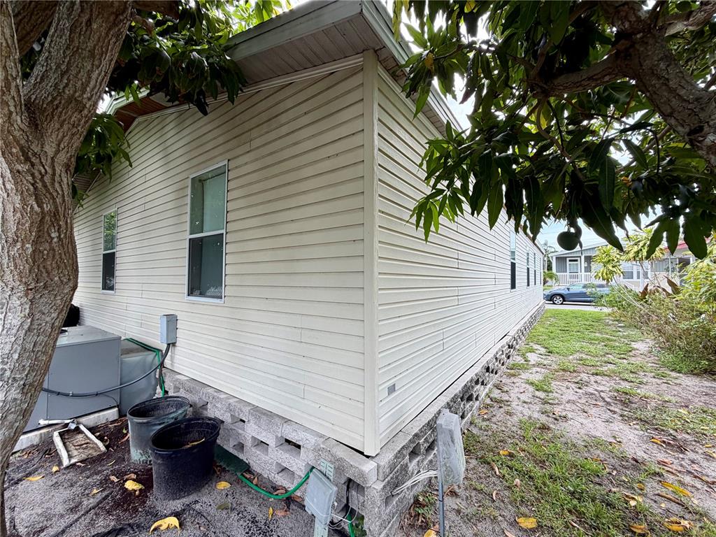 The exterior of a light-colored mobile home features vinyl siding and a concrete block foundation — 34066 AVOCADO DRIVE N, PINELLAS PARK, FL
