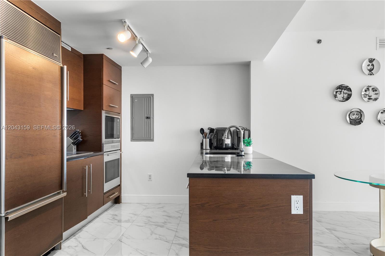 A modern kitchen features dark wood cabinetry, a black countertop island, and marble-patterned tile flooring — 465 Brickell Ave # 5505, Miami FL 33131, MIAMI, FL
