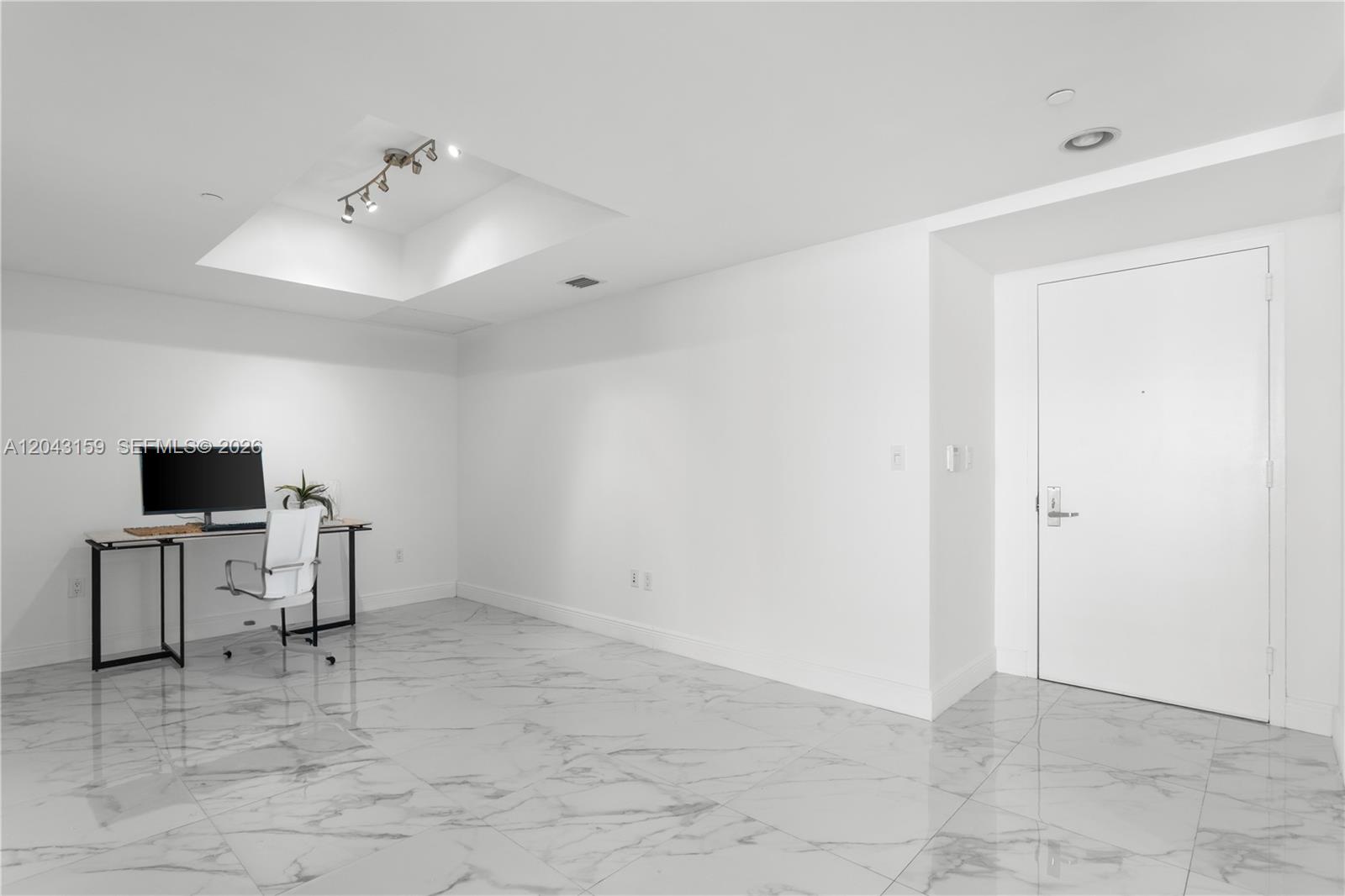 A minimalist room features white walls, marble-patterned tile flooring, a desk, and a white door — 465 Brickell Ave # 5505, Miami FL 33131, MIAMI, FL