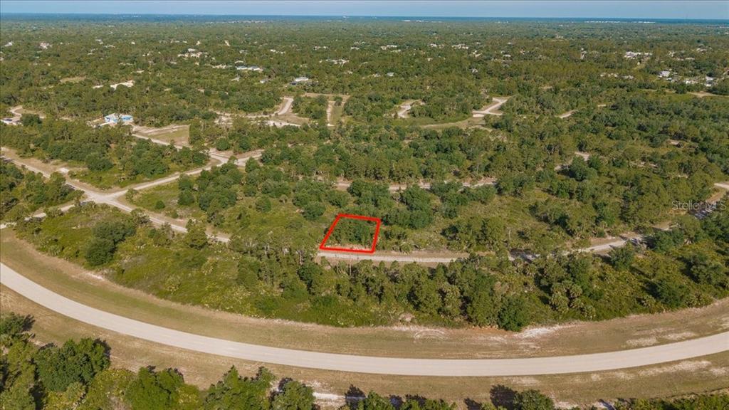 An aerial view shows a vacant, rectangular plot of land outlined in red among trees — WINTERVILLE CIRCLE, NORTH PORT, FL