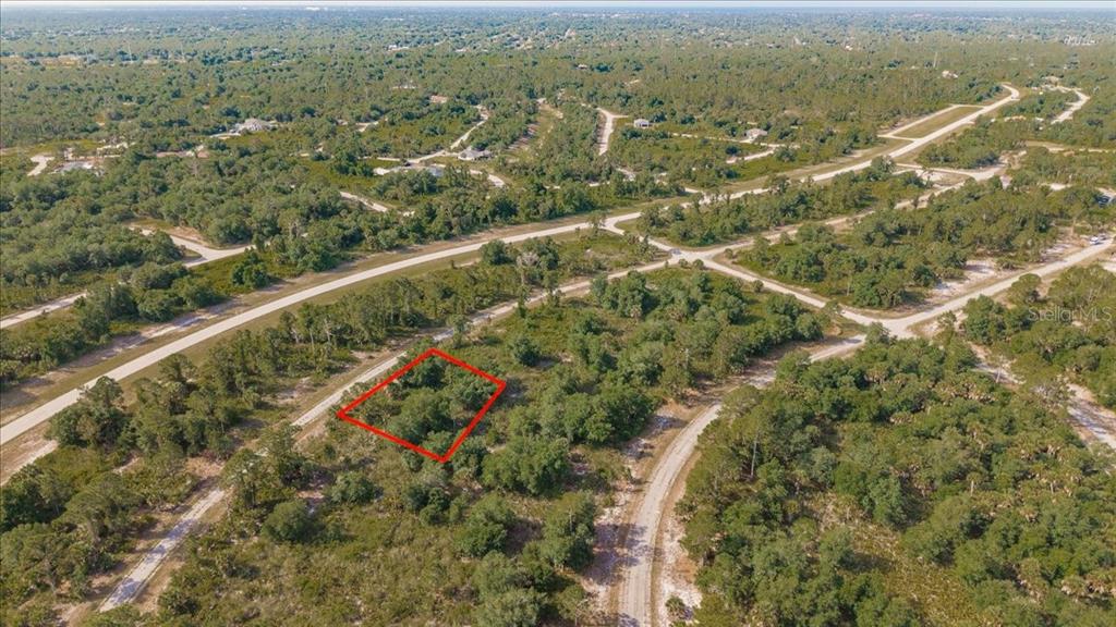An aerial view shows a rectangular plot of land outlined in red amidst wooded terrain — WINTERVILLE CIRCLE, NORTH PORT, FL