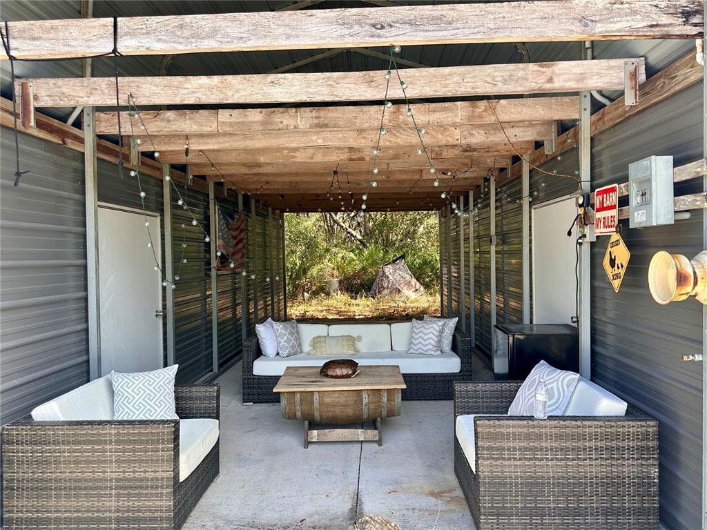 An open-air patio features wicker furniture, a barrel coffee table, and string lights — 4125 TIGER CREEK TRL, LAKE WALES, FL
