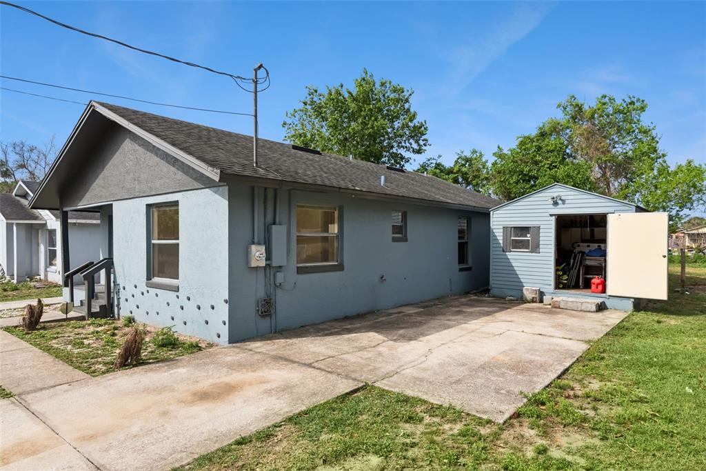 A blue house with a concrete driveway and a detached shed under a clear sky — 2260 DOLARWAY STREET, SANFORD, FL