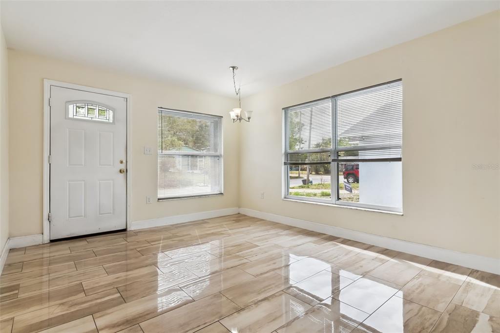 A bright dining room features light-colored walls, glossy wood-look tile flooring, and two large windows — 2260 DOLARWAY STREET, SANFORD, FL