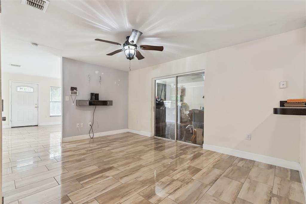 A living room with wood-look tile flooring, a ceiling fan, and sliding glass patio doors — 2260 DOLARWAY STREET, SANFORD, FL