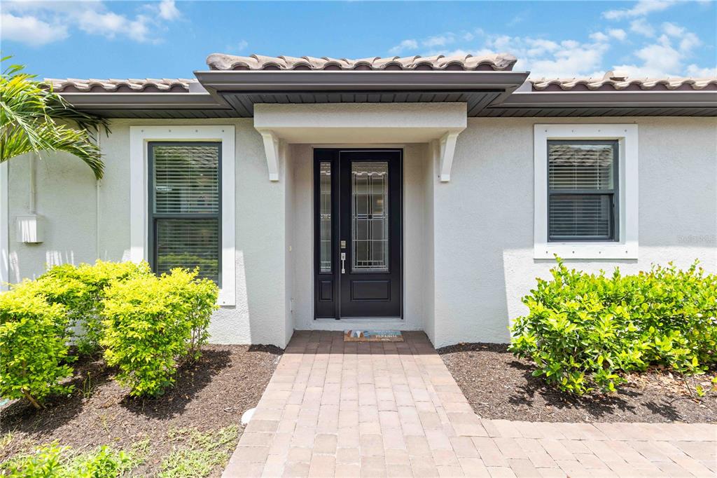 A front entrance features a black door with glass panels and a paved walkway — 6242 GRANDVIEW HILL COURT, BRADENTON, FL