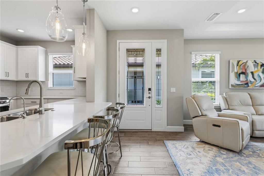 A kitchen with a white island and bar stools sits adjacent to a living area — 6242 GRANDVIEW HILL COURT, BRADENTON, FL