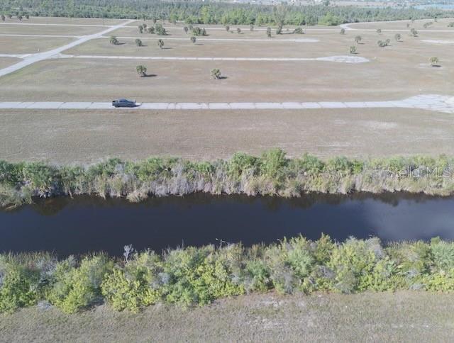 An aerial view shows a vacant lot with a paved road, scattered trees, and a canal — 14381 KING PHILLIP COURT, PLACIDA, FL