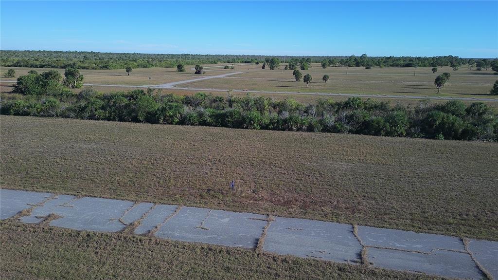 An aerial view shows a vacant, grassy lot bordering a cracked asphalt road — 14381 KING PHILLIP COURT, PLACIDA, FL