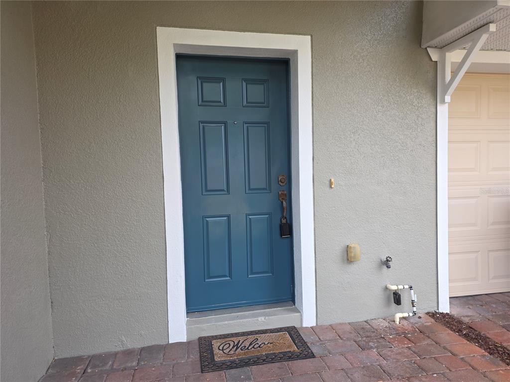 A blue front door with a white frame sits on a brick porch — 16661 CEDAR CREST DRIVE, ORLANDO, FL