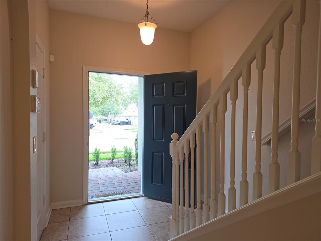 An entryway features tiled flooring, a staircase with a white railing, and an open front door — 16661 CEDAR CREST DRIVE, ORLANDO, FL