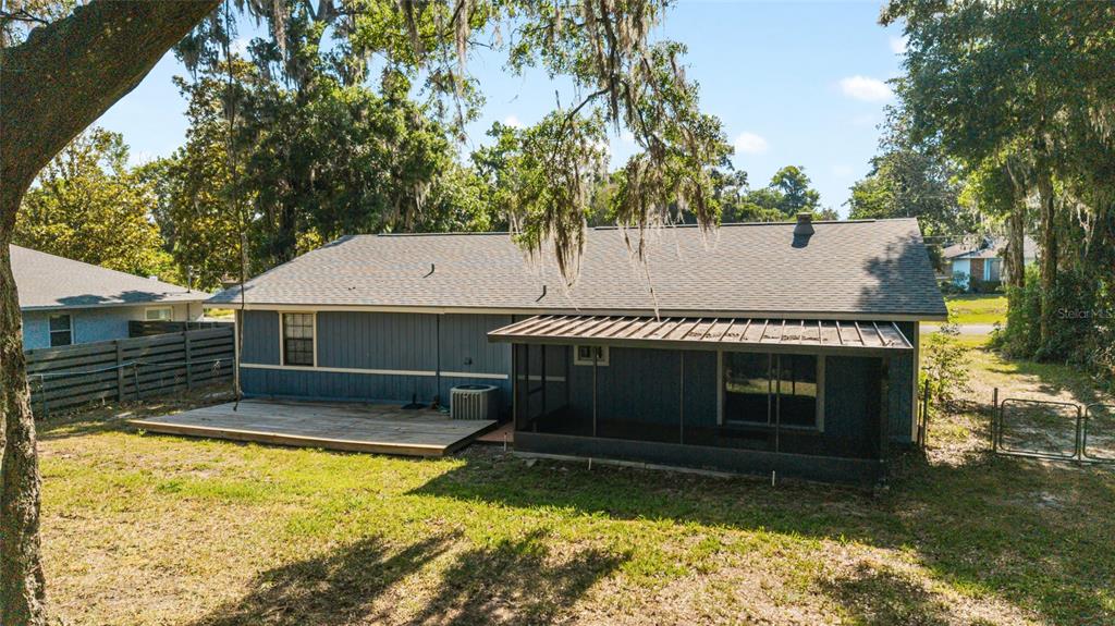 The back of a blue house features a wooden deck and a screened-in porch — 5026 SE 33RD TERRACE, OCALA, FL