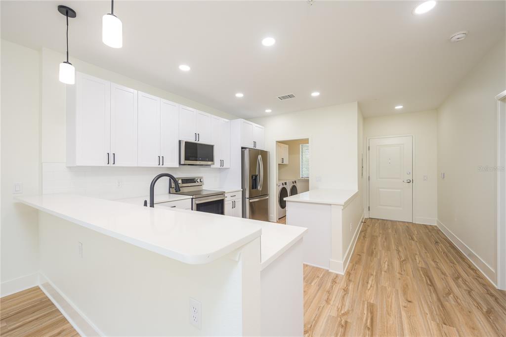 A modern kitchen features white cabinets, stainless steel appliances, and a breakfast bar — 419 SE 1ST AVENUE UNIT 201, OCALA, FL