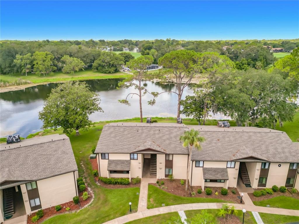 An aerial view of a multi-unit residential building situated next to a lake and trees — 655 MIDWAY DRIVE UNIT A, OCALA, FL