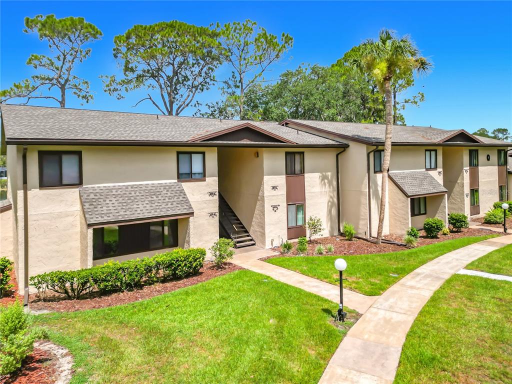 A two-story apartment building with beige stucco walls, brown trim, and a concrete walkway — 655 MIDWAY DRIVE UNIT A, OCALA, FL