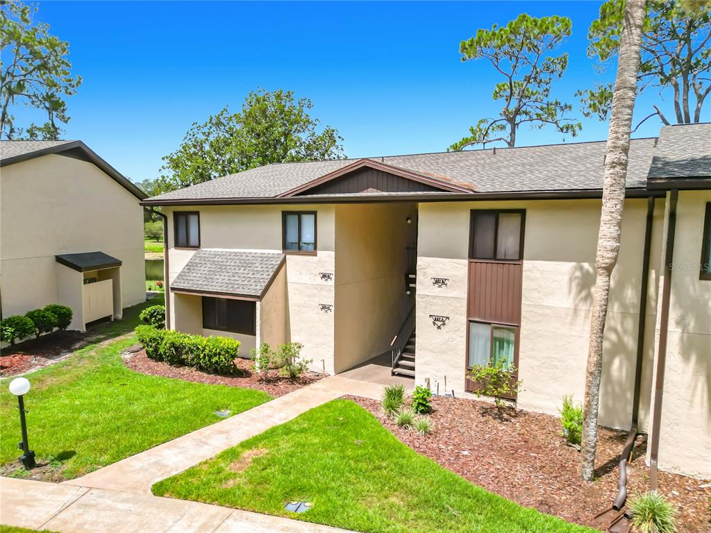 A two-story tan apartment building with a central breezeway and a landscaped front lawn — 655 MIDWAY DRIVE UNIT A, OCALA, FL
