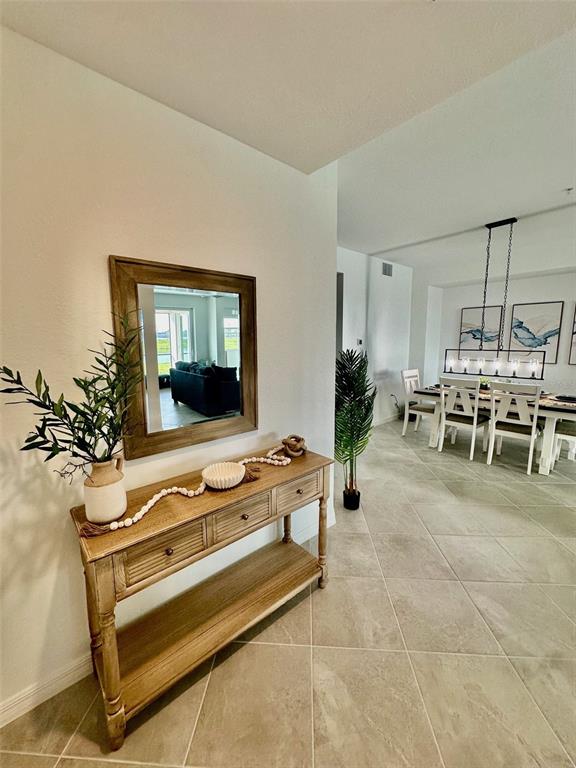 A wooden console table with a mirror sits in an entryway near a dining area — 12680 RADIANCE COURT UNIT 102, VENICE, FL