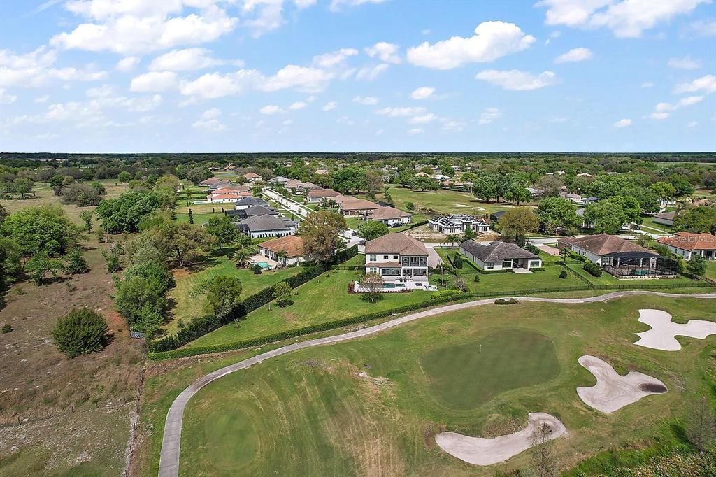 An aerial view shows a large house with a pool overlooking a golf course — 25868 CROSSINGS BLUFF LANE, SORRENTO, FL