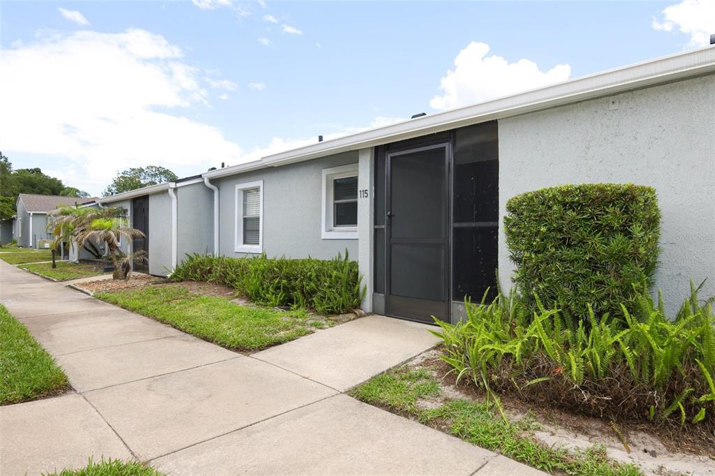 A single-story gray stucco building with a screen door and a concrete walkway — 115 DORCHESTER SQUARE, LAKE MARY, FL
