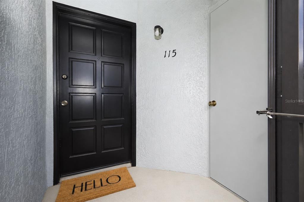 A black front door with a welcome mat and the number 115 on the wall — 115 DORCHESTER SQUARE, LAKE MARY, FL