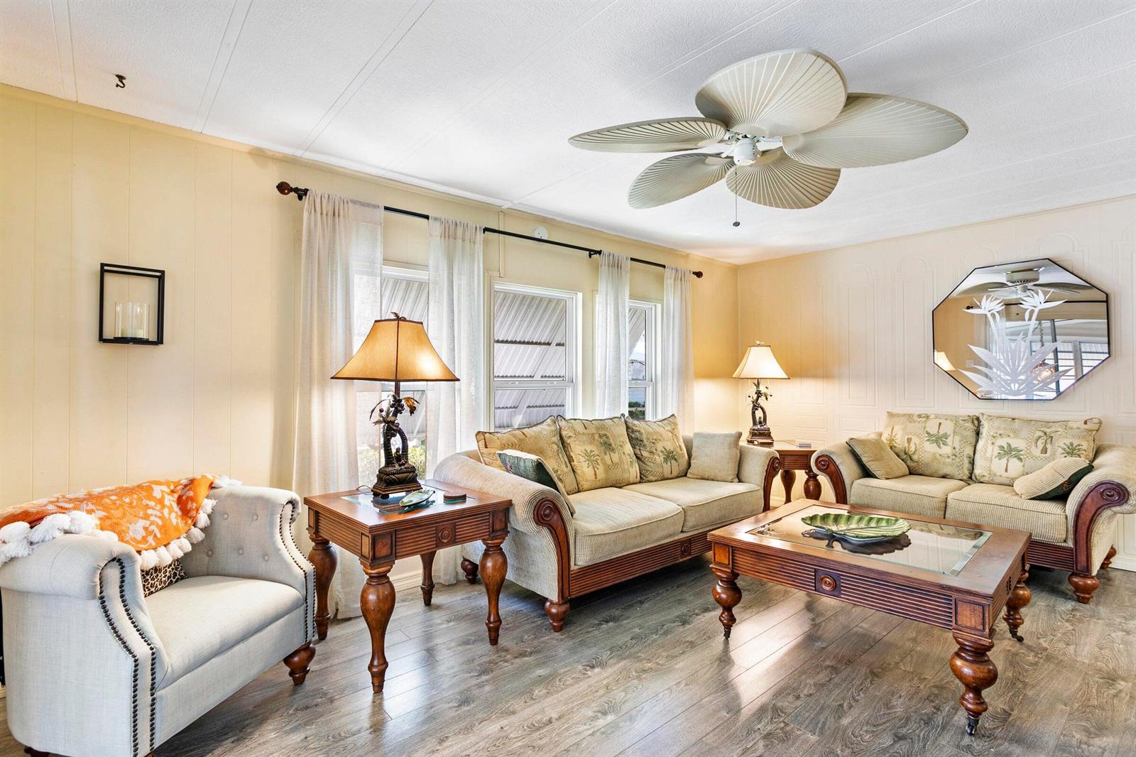 A living room features light-colored walls, wood-look flooring, two sofas, an armchair, and a fan — 37039 Exuma Bay, Boynton Beach FL 33436, BOYNTON BEACH, FL