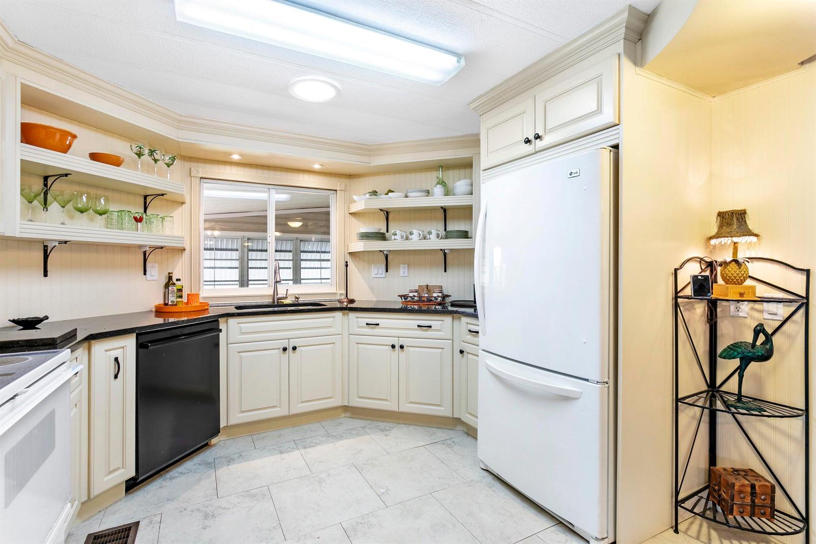 A kitchen features white cabinets, black countertops, a white refrigerator, and open shelving — 37039 Exuma Bay, Boynton Beach FL 33436, BOYNTON BEACH, FL