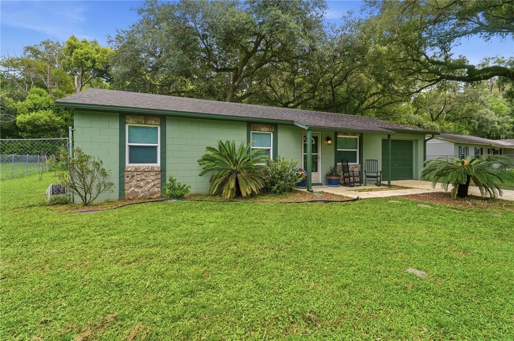 A single-story green concrete block house with a stone facade and a front porch — 2120 TANGLEWOOD DRIVE, ORANGE CITY, FL