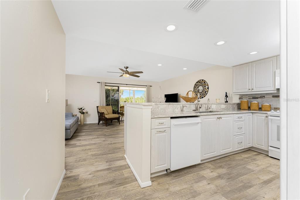 A kitchen with white cabinets and a dishwasher opens into a living area with flooring — 6800 PLACIDA ROAD UNIT TH2, 1B, ENGLEWOOD, FL