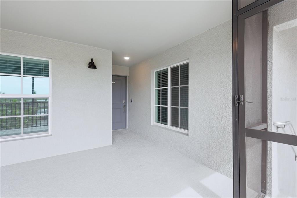 A covered entryway features a gray door, two windows, and a textured white wall — 18923 SCALLOP LOOP UNIT 205, BRADENTON, FL