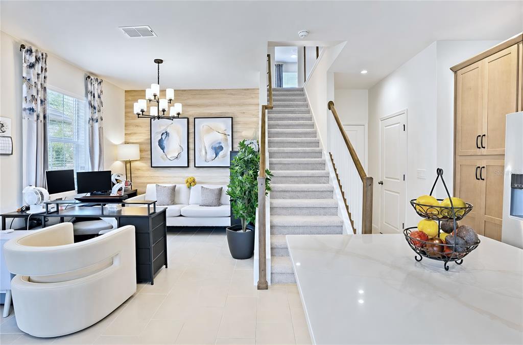 A home office area with a desk and sofa sits beside a carpeted staircase — 1120 LAKESHORE BREEZE PLACE, KISSIMMEE, FL