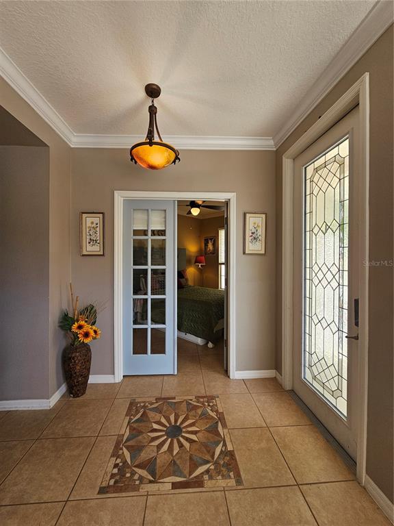 An entryway features tile flooring with a decorative inlay, a pendant light, and a glass-paneled door — 25147 IRONWEDGE DRIVE, SORRENTO, FL