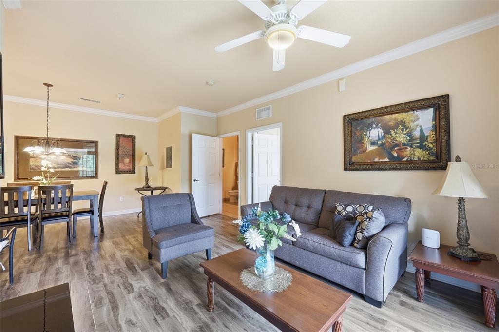 A living room and dining area with wood-look flooring, a ceiling fan, and neutral walls — 8020 TUSCANY WAY UNIT 6206, DAVENPORT, FL