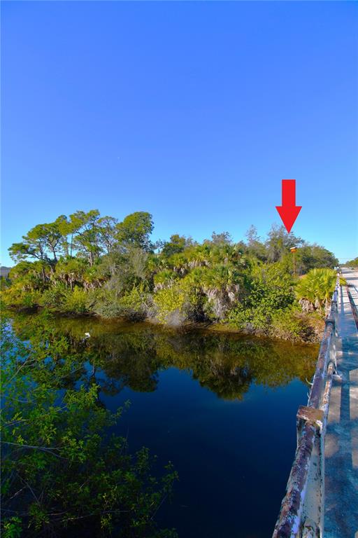A red arrow points toward a wooded area next to a calm body of water — 17255 WINTERGARDEN AVENUE, PORT CHARLOTTE, FL