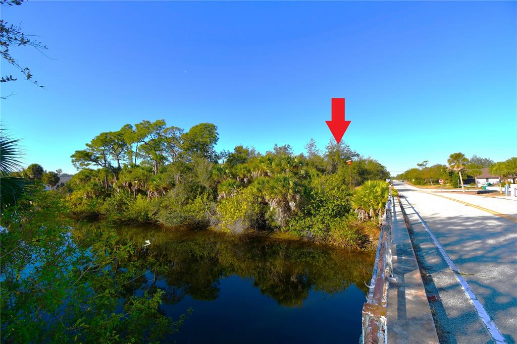 A red arrow points to a wooded lot next to a road and a canal — 17255 WINTERGARDEN AVENUE, PORT CHARLOTTE, FL