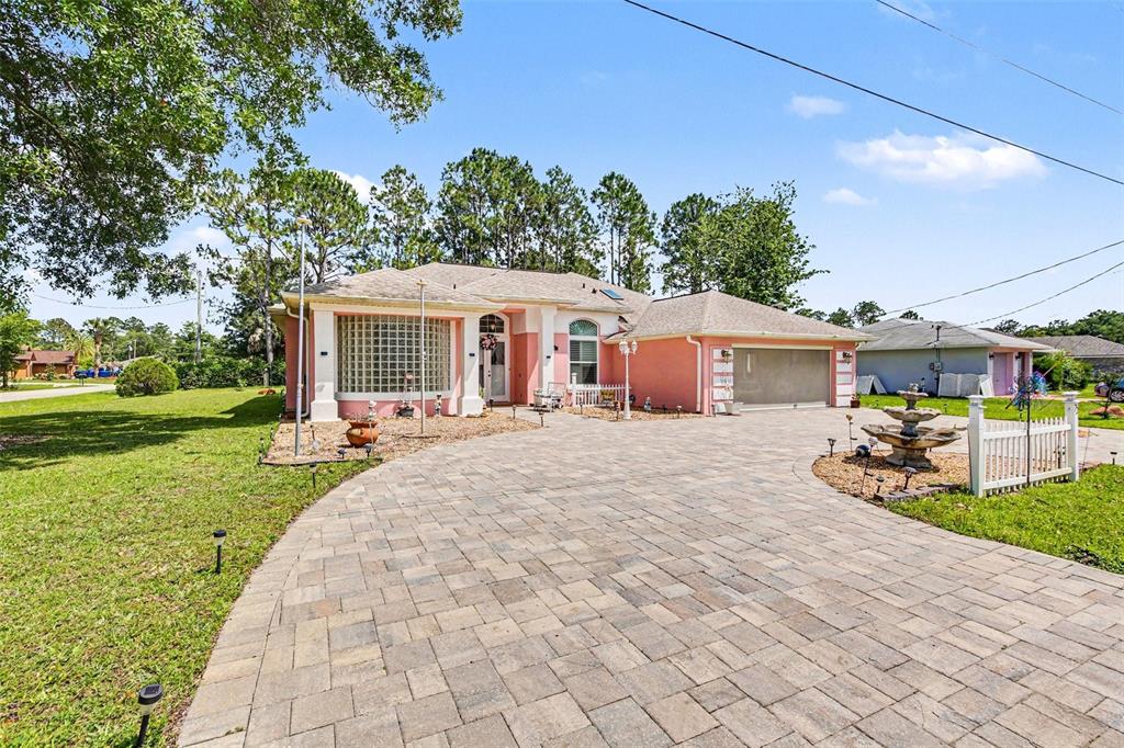 A pink house with a paved driveway, glass block window, and a front yard fountain — 72 WHITE STAR DRIVE, PALM COAST, FL