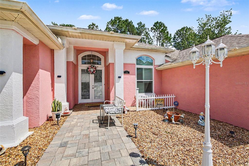 A pink house exterior features a stone walkway, a white bench, and a lamp post — 72 WHITE STAR DRIVE, PALM COAST, FL