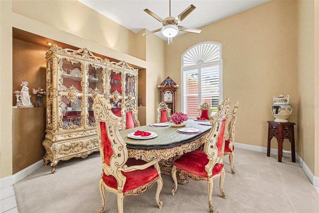 A formal dining room features ornate furniture, a ceiling fan, and a large arched window — 72 WHITE STAR DRIVE, PALM COAST, FL