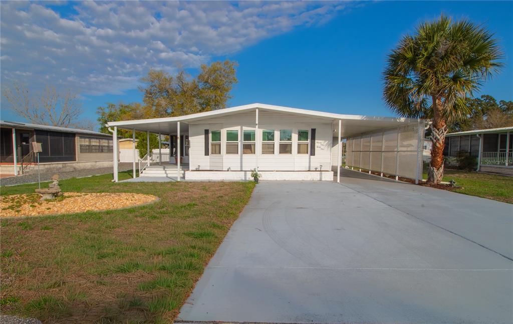 A white manufactured home with a carport, a concrete driveway, and a palm tree — 9141 SALISBURY DRIVE, BROOKSVILLE, FL