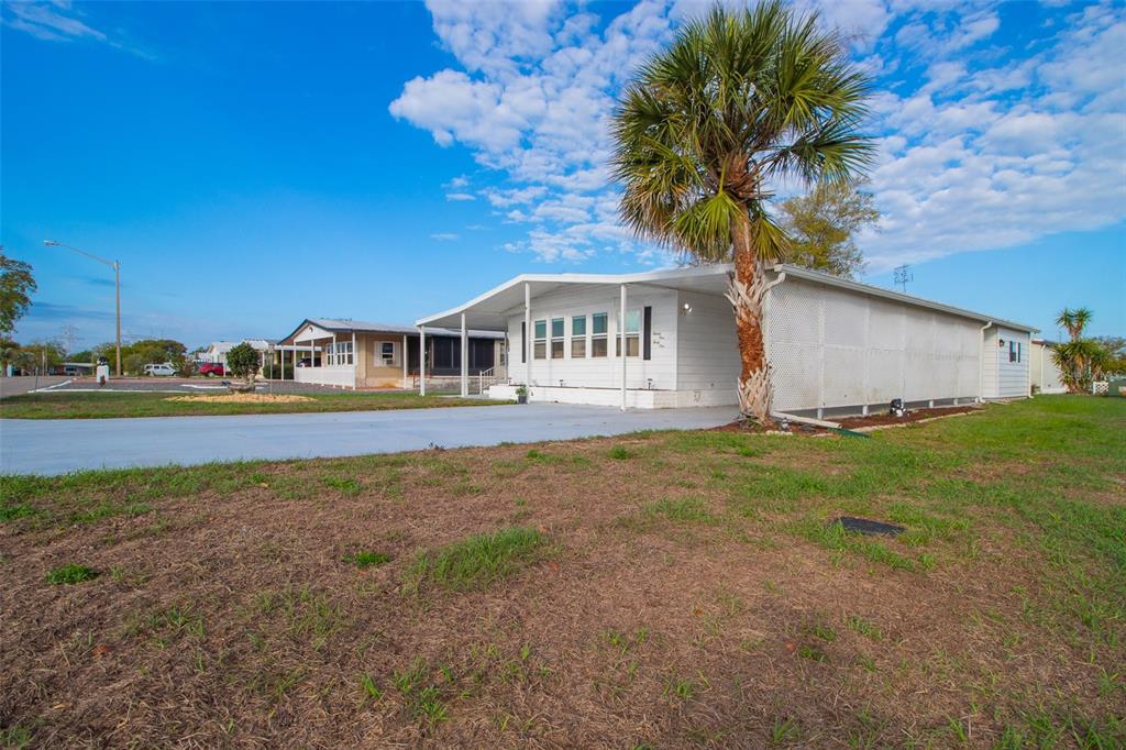 A white mobile home with a carport and a palm tree in the front yard — 9141 SALISBURY DRIVE, BROOKSVILLE, FL