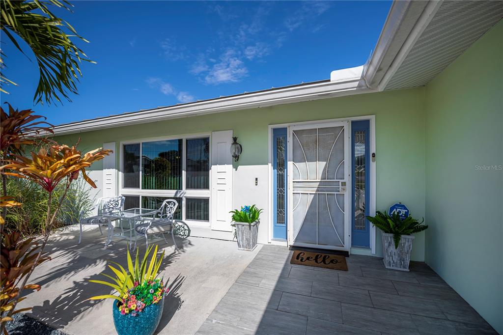 A light green house exterior features a front porch with a white screen door — 1354 AQUI ESTA DRIVE, PUNTA GORDA, FL