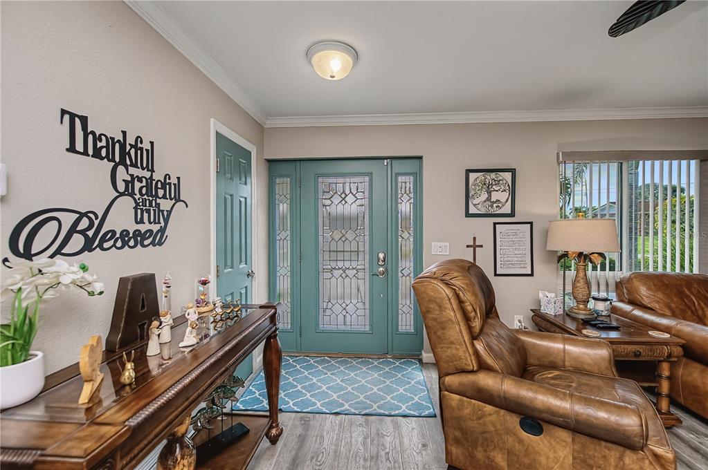 An entryway features a teal front door, wood-look flooring, and a console table with decor — 1354 AQUI ESTA DRIVE, PUNTA GORDA, FL
