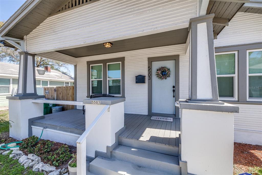 A white house features a covered front porch with gray wooden decking and two columns — 5503 N 9TH STREET, TAMPA, FL