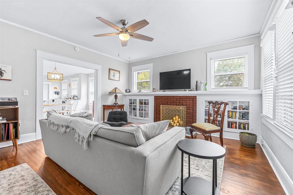 A living room features a brick fireplace, built-in cabinets, hardwood floors, and a ceiling fan — 5503 N 9TH STREET, TAMPA, FL